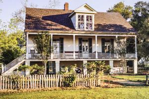 une vieille maison avec une clôture blanche dans l'établissement Vintage Louisiana Vacation Rental Home, à New Roads