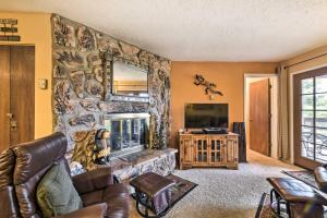 a living room with a stone wall with a fireplace at Mtn-View Angel Fire Condo, Less Than 1 Mile to Resort! in Angel Fire