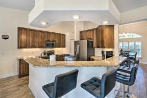 une cuisine avec des placards en bois et un comptoir avec des tabourets de bar dans l'établissement Beautiful Port Charlotte Home, 6 Mi to Beach!, à Port Charlotte