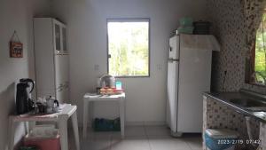 uma cozinha com um frigorífico branco e uma janela em Chale do vale em Porto Seguro