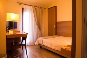 a bedroom with a bed and a desk and a window at Country House Corte Del Sole in Campolungo