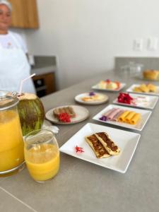 una mesa con platos de comida y vasos de zumo de naranja en Pousada Praia do Patacho en Pôrto de Pedras