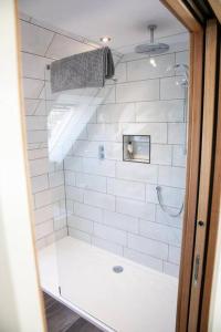 La salle de bains est pourvue d'une douche avec du carrelage blanc. dans l'établissement The Roost - a bird's eye view in the countryside, à Cullompton