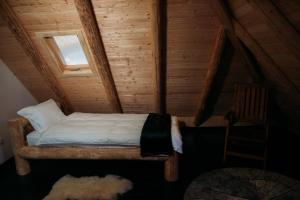 Cama en una cabaña de madera con ventana en Huta Village, en Piatra