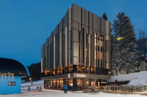 Un bâtiment avec des personnes debout à l'extérieur dans la neige dans l'établissement Galeria Jahorina Luxury Ski Apartments and Restaurant, à Jahorina