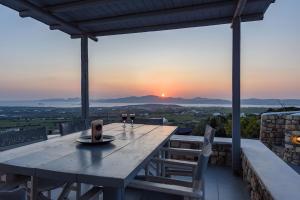 a table with two glasses of wine on a balcony with the sunset at Villa Sunset in Aliki