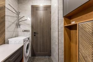 a bathroom with a washing machine and a wooden door at Pajūrio Oazė MG13 in Klaipėda +37 photos
