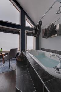 a bathroom with a tub and a chair and windows at Coastal Lookout Suites in Corner Brook