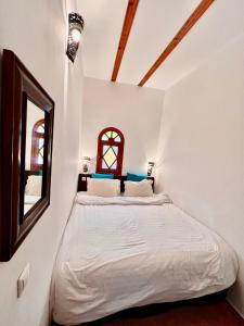 a bedroom with a white bed and a window at Riad Dar Hanae in Tetouan