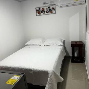 1 dormitorio con cama blanca y mesita de noche en Habitación confortable y terraza Hamacas Coveñas, en Coveñas