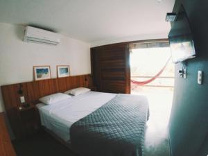 um quarto com uma cama grande e uma janela em Bangalô Patuá em Barra Grande