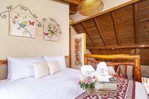 a bedroom with a white bed with flowers on a table at Casinha Ipê Roxo - Condomínio Quinta do Rosário in Pirenópolis +77 photos