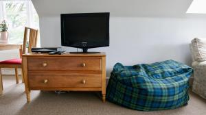 TV en la parte superior de una cómoda con sofá en Chauffeurs Cottage, en Comrie