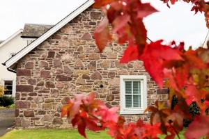 una casa de piedra con hojas rojas delante de ella en Chauffeurs Cottage, en Comrie