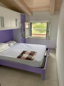 ein Schlafzimmer mit einem lila Bett und einem Fenster in der Unterkunft casa montauro in Stalettì