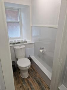 a white bathroom with a toilet and a bath tub at Baile Apartment Central Inverness in Inverness