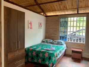 sypialnia z łóżkiem z zielonym kocem i oknem w obiekcie Casa de campo ideal para descanso w mieście Villavicencio
