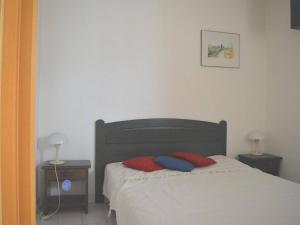 a bed with two red and blue pillows on it at Appartement Argelès-sur-Mer, 3 pièces, 6 personnes - FR-1-225-453 in Argelès-sur-Mer