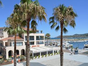 a hotel with palm trees in front of a marina at Appartement Argelès-sur-Mer, 3 pièces, 6 personnes - FR-1-225-453 in Argelès-sur-Mer