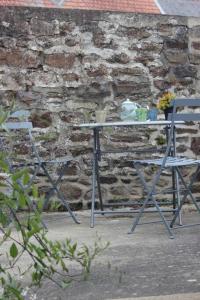 una mesa y una silla frente a una pared de ladrillo en Appartement cocoon dans maison du XVIIème siècle, en Fougères