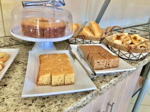 a counter with several different types of bread and cakes at Hotel pousada estação dos devotos in Aparecida