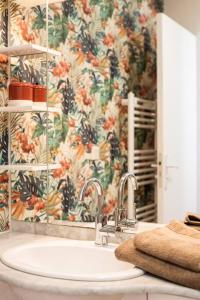 baño con lavabo y papel pintado con motivos florales en Appartement cocoon dans maison du XVIIème siècle, en Fougères