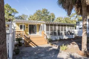 a yellow house with a wooden porch and stairs at Longboard House in Tybee Island