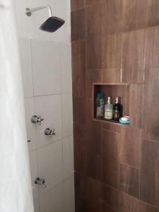ein Bad mit einer Dusche und einer Holzwand in der Unterkunft Departamento cómodo y hermoso a mts de la playa in San Crisanto