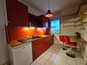 a kitchen with red cabinets and a sink and a counter at T2 Parc & Cité Internationale in Caluire-et-Cuire
