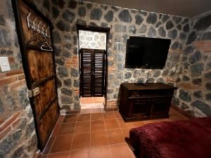 Habitación con TV en una pared de piedra. en Villas Gasconia, en Antigua Guatemala