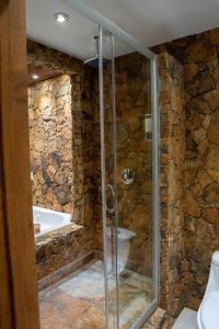 uma casa de banho em pedra com um chuveiro e uma banheira em Sueños Resort em El Porvenir
