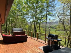 een houten terras met een grill en een grill bij Wonderful cabin tucked in the woods /w Hot tub in Mountain City