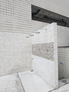 y baño con ducha y azulejos blancos. en Condomínio Terraço do Atlântico, en Fortaleza