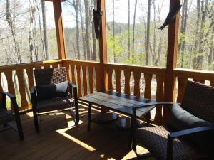 un porche cubierto con mesa y sillas en Two Rivers Cabins - The Mountaintop en Brevard