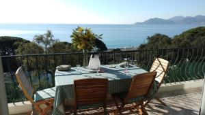 a table and chairs on a balcony with a view of the ocean at Appartement vue mer panoramique, plage 150M, terrasse, parking privé, clim in Cannes