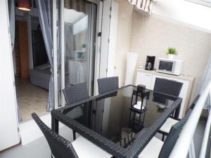einen Balkon mit einem Glastisch und Stühlen in der Unterkunft Studio Marseillan-Plage, 1 pièce, 6 personnes - FR-1-326-452 in Marseillan