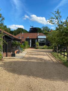 a house with a gravel driveway in front of it at Brundish Suffolk Large 4-Bed Barn Stunning! in Woodbridge