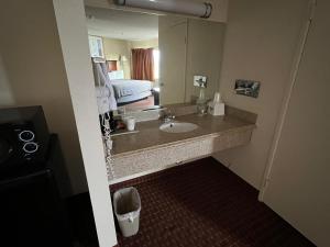 La salle de bains est pourvue d'un lavabo et d'un grand miroir. dans l'établissement Days Inn & Suites by Wyndham Rancho Cordova, à Rancho Cordova