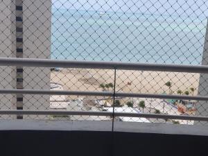 a chain link fence with a view of a beach at Condomínio Porto de Iracema in Fortaleza