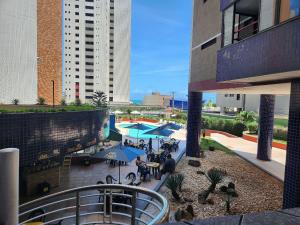 un patio al aire libre con mesas y sombrillas en un edificio en Condomínio Porto de Iracema, en Fortaleza
