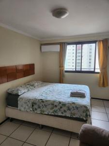 a bedroom with a bed and a large window at Condomínio Porto de Iracema in Fortaleza