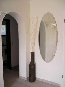 ein Spiegel und eine Vase mit Blumen im Flur in der Unterkunft Haus Ellbogen in Momlingen