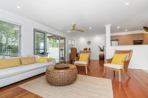 een woonkamer met een bank, stoelen en een tafel bij Browning Street Sea Drift in Byron Bay