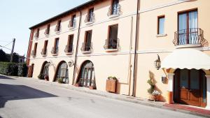 a large building with a white awning next to a street at Hotel Alla Nave in Masi