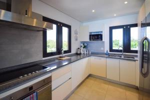 cocina grande con armarios blancos y ventanas en Beachfront Luxury with Incredible Ocean Views apts by Bluescape, en Christ Church