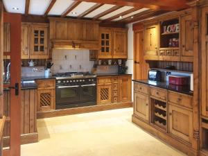 a large kitchen with wooden cabinets and a stove at Flatts Barn in Hebden