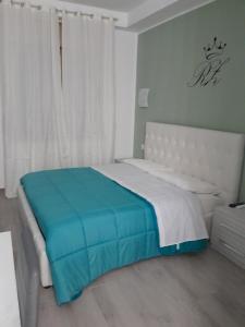 1 dormitorio con cama blanca y manta azul en New zarà, en Villa San Giovanni