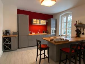 cocina con paredes rojas y barra con sillas en Charmantes Gästehaus Maya im Schloß und Hofgut Langenzell, en Wiesenbach