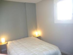 ein Schlafzimmer mit einem weißen Bett mit zwei Leuchten in der Unterkunft Appartement Marseillan-Plage, 3 pièces, 5 personnes - FR-1-387-121 in Marseillan