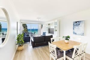 a dining room and living room with a table and chairs at Luxury Manly Beachfront Apartment in Sydney